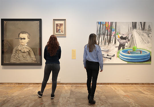 Two women contemplating the works displayed in the Estudi General Hall.